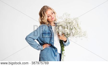 Stylish Young Blonde Woman With A Bouquet Of Gypsophila. Portrait On A White Background. Happy Woman