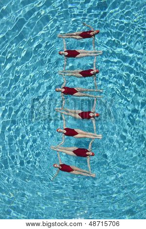Grupo de nadadores sincronizados formando una escalera en la piscina