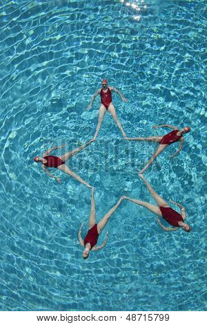Vista elevada de nadadores sincronizados formando una forma de estrella en la piscina