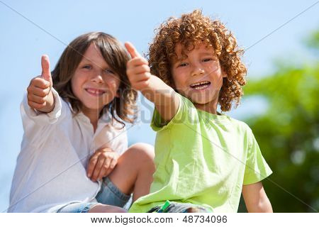 Dwa Cute chłopców robi kciuki do góry na zewnątrz.