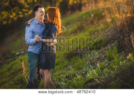 couple kissing standing outdoos among bushes