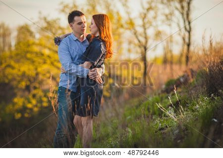 couple kissing standing outdoos among bushes
