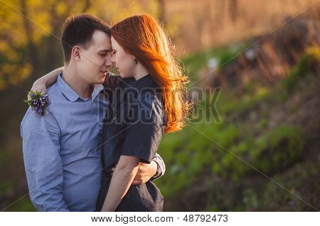 couple kissing standing outdoos among bushes