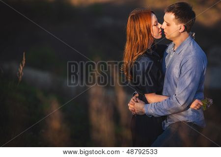 couple kissing standing outdoos among bushes