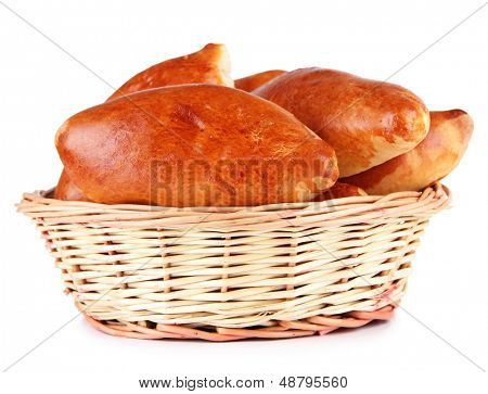 Empanadillas al horno frescos en cesta de mimbre, aislados en blanco