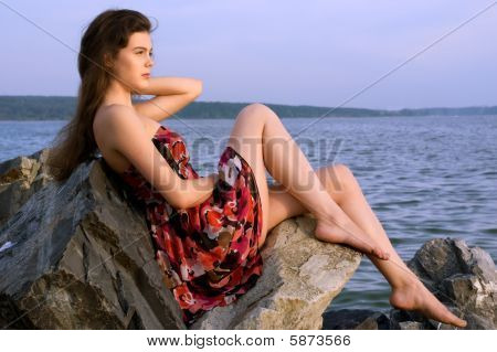 Girl sit on rock on sea coast