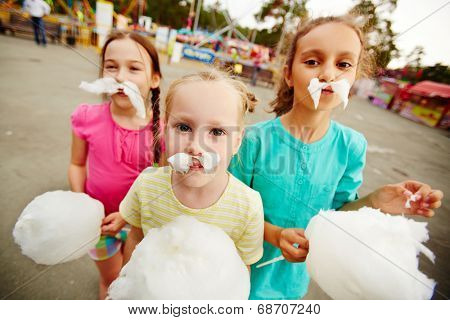 Image of funny girls with cotton candy posing on playground outdoors 
