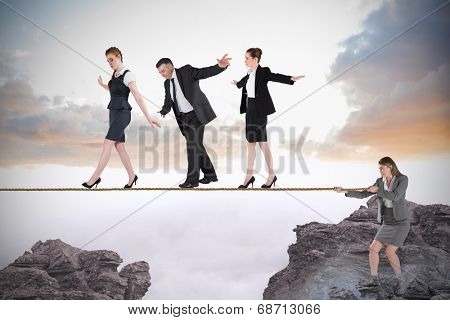 Young businesswoman pulling a tightrope for business people against rocky landscape