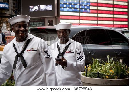 NEW YORK - MAY 23: Two US Navy sailors on liberty pass the lighted US Flag on the Armed Forces Recruiting Center in Times Square during Fleet Week NY.                                                  
