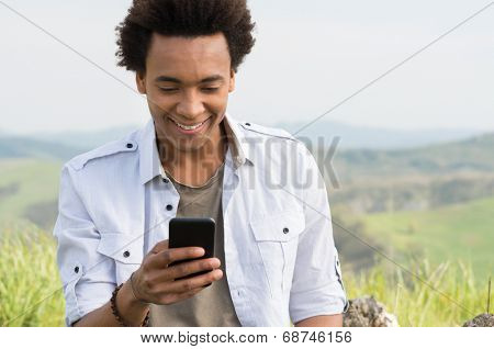 Young African Man Looking At Mobile Phone