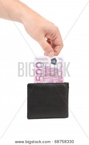 Man's hand pulling cash from the wallet.
