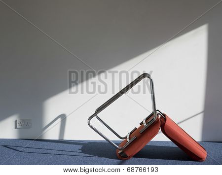 Side view of an upturned office chair casting shadow on wall