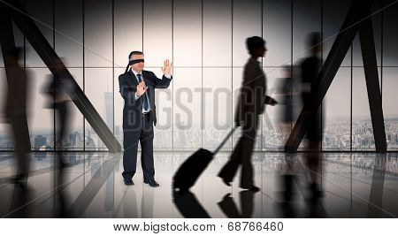 Mature businessman in a blindfold against room with large window looking on city