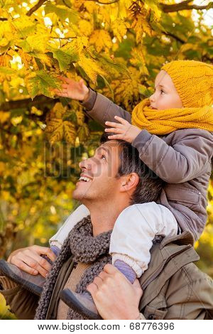father enjoying colder season outdoor in park teaching leaves