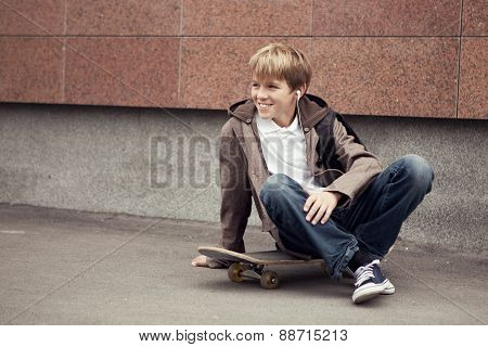 School Teen Sits On Skateboard Near School