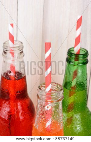 Closeup of soda bottle necks with straws. 