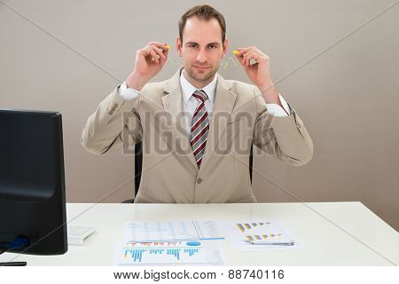 Businessman Inserting Earplug In Ears