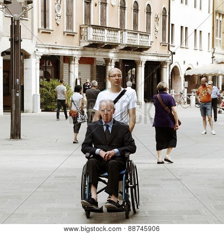 Venice, Mestre-june 29, 2014: Young Man Pushing A Senior Man In A Wheelchair On Piazza Erminio Ferre