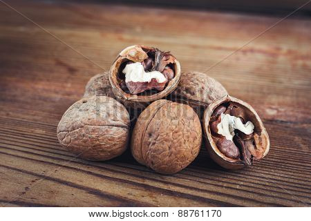 Walnut kernels and whole walnuts wood background