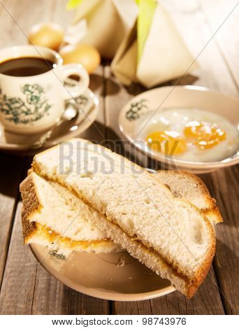 Steaming traditional oriental Chinese kopitiam style dark coffee in vintage mug and saucer with coffee beans. Fractal on the cup is generic print. Soft focus with dramatic light on wooden background.