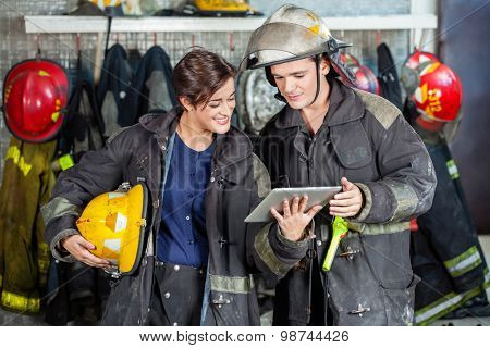 Young male and female firefighters using digital tablet at fire station