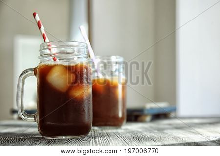 Mason jar with cold brew coffee and straw on wooden table