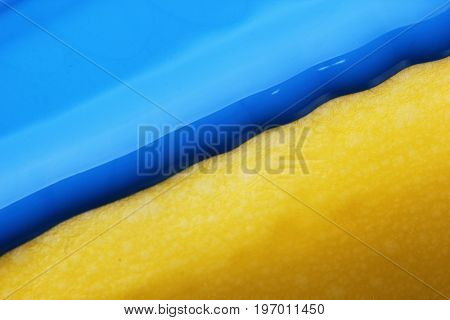 Pouring blue paint over yellow background, macro closeup.Texture.Abstract