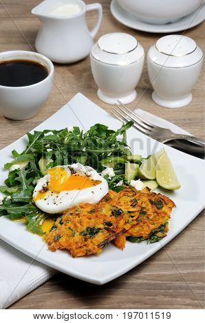 Brunch Idea. Egg poached with pumpkin spinach pancakes and garnish from arugula avocado mint leaves and ricotta