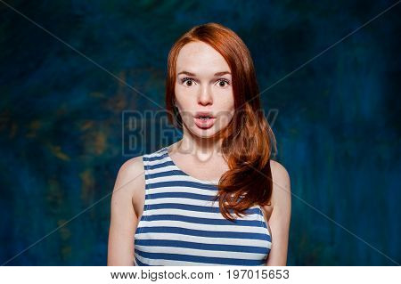 frightened redhead girl in vest oner dark blue background
