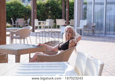 blonde girl sitting at the beach restaurant