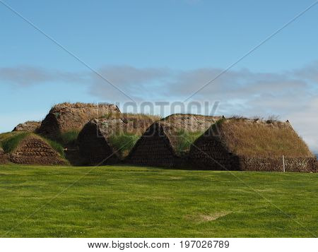 Glaumber - open-air folk museum - tradicional icelandic houses with turf roof and walls with green grass and blue sky