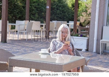 blonde girl sitting at the beach restaurant coffee drinkers