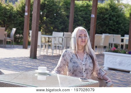 blonde girl sitting at the beach restaurant coffee drinkers