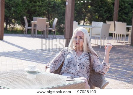 blonde girl sitting at the beach restaurant coffee drinkers