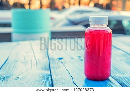 Close up soft fruit drink in plastic bottle on wooden table in outdoors restaurant