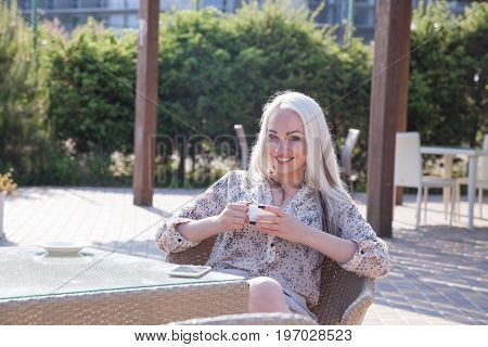 blonde girl sitting at the beach restaurant coffee drinkers
