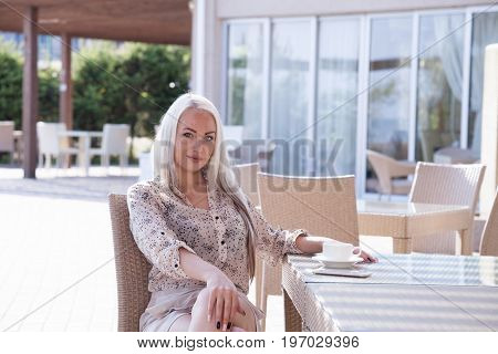 blonde girl sitting at the beach restaurant coffee drinkers