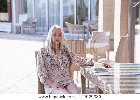 blonde girl sitting at the beach restaurant coffee drinkers