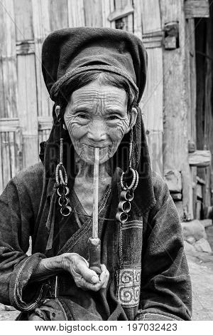 Phongsali Privince Laos - 24.July 2010: senior adult hill tribe woman in traditional clothes smoke her pipe