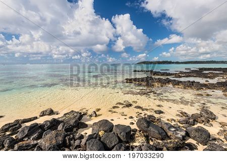 Wide-angle view of the Blue Bay Marine Park Mauritius Mahebourg Indian Ocean. Stones in the foreground. Polarizer filter used.
