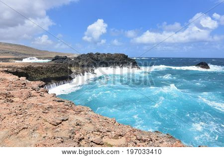 Water running down the rock sea cliffs by Andicuri Beach in Aruba.