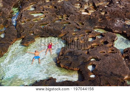 Family beach holiday lifestyle. Happy couple relax in natural sea pool at Angel's Billabong on Pasih Uug. Best travel destinations on Bali island. Nusa Penida day tour popular place. Leisure activity.
