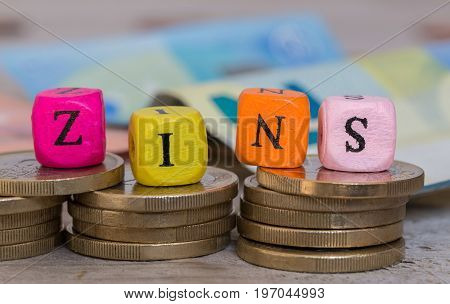 Zins (in german Interest) alphabet cube on coins concept.