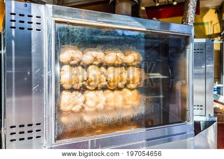 Rotisserie chicken machine with many plump birds roasting