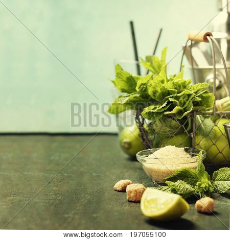 Mojito cocktail ingredients (fresh mint, lime, ice) on rustick background