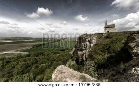 Romantic Drazovsky church on the hill Slovakia. Cloudscaoe over dark country.
