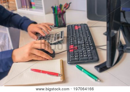 man writing notes from computer on wooden table. Man hand with pen calculator and computer on wooden table - color / Old Polaroid