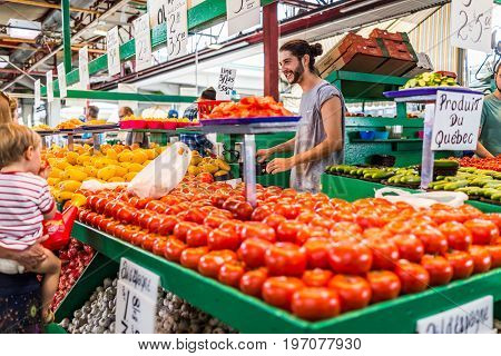 Montreal, Canada - May 28, 2017: Happy Smiling Man Selling Produce By Tomato Stand With Sample Slice
