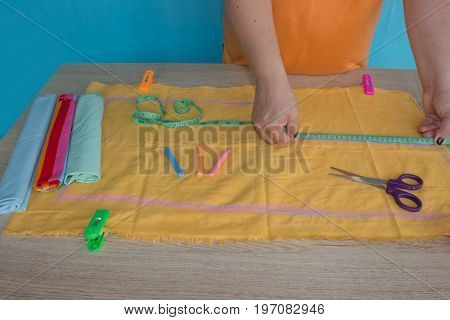 Tailor cutting fabric using large scissors or shears as he follows the chalk markings of the pattern close up of his hands. Woman's Hand Sewing Quilt
