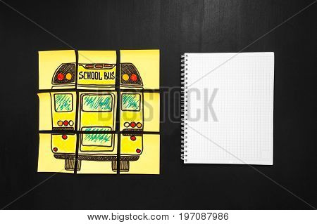 Back to school background with title "Back to school" and "school bus" written on the yellow pieces of paper and notebook for yout text are on the chalkboard